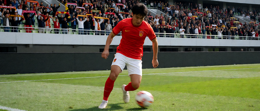 足球比赛现场球员在中场拼抢，看台上球迷挥动围巾